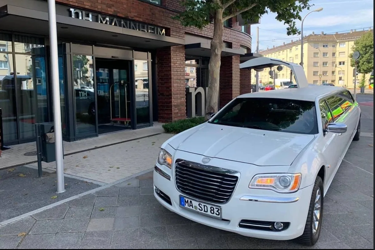 Weißer Chrysler 300C Stretchlimousine mit geöffneter Flügeltür vor dem Eingang eines Hotels