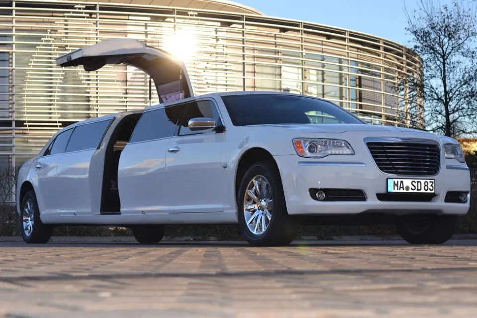 Weißer Chrysler 300C mit geöffneter Flügeltür im Abendlicht