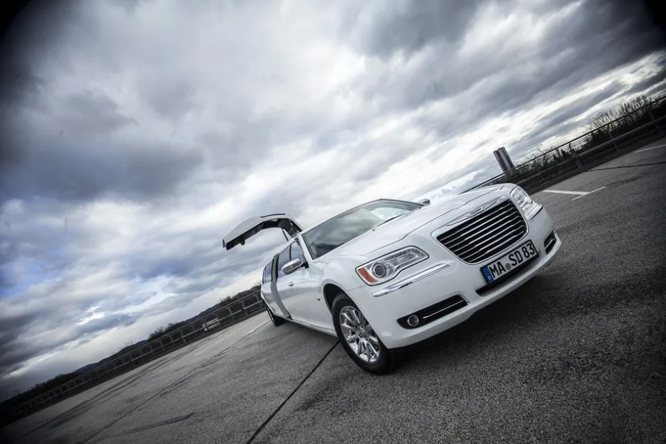 Vorschaubild zum STARDRIVE-Video: weißer Chrysler 300C mit Flügeltür vor dramatischem Wolkenhimmel