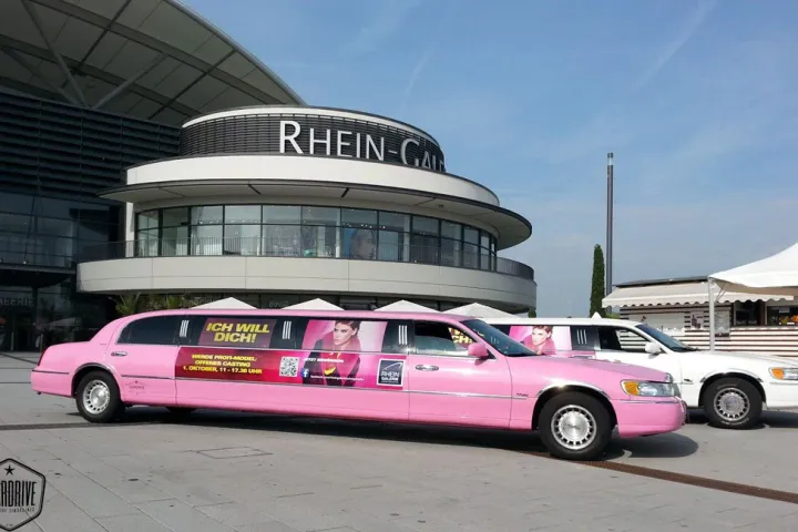 Pinke Limousine mit Werbebeklebung vor einem Veranstaltungsgebäude