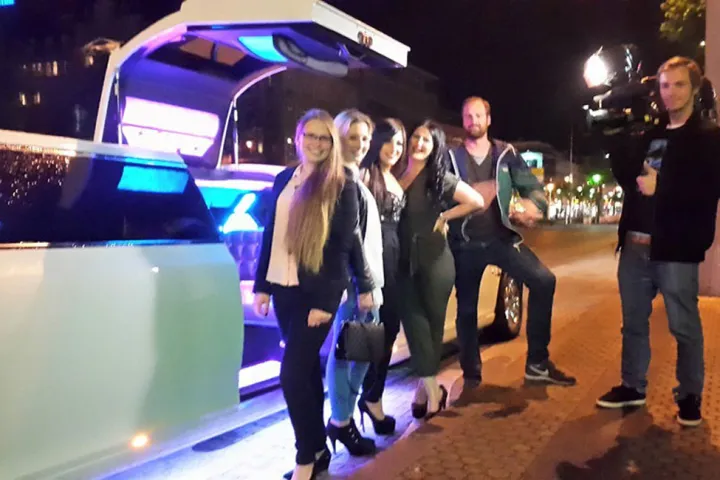 Gäste vor einer Limousine mit blau beleuchtetem Innenraum