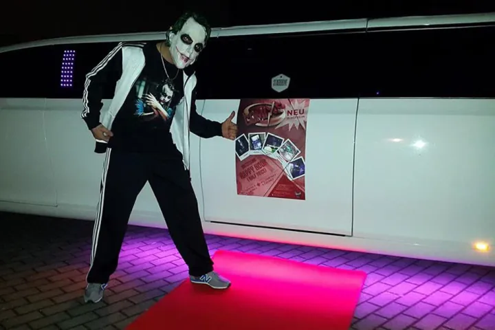 Verkleideter Gast auf rotem Teppich vor einer Limousine
