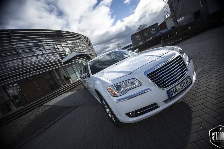 Weißer Chrysler 300C vor einem modernen Gebäude, aus der Froschperspektive