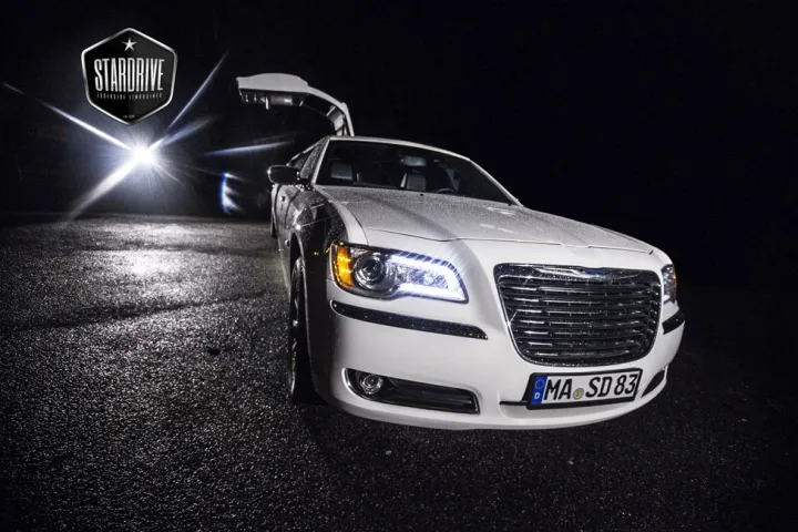 Weißer Chrysler 300C mit Flügeltür bei Nacht im Scheinwerferlicht