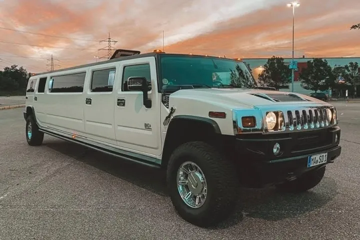 Weißer Hummer H2 als Stretch-Limousine im Abendrot auf einem Parkplatz