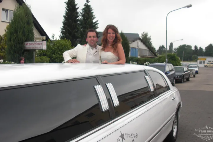 Brautpaar hinter der weißen Stretch-Limousine