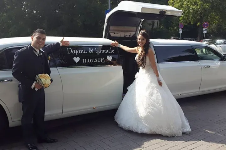 Brautpaar vor der weißen Stretch-Limousine mit geöffnetem Kofferraum