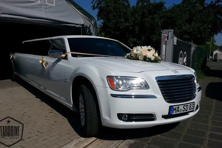 Weißer Chrysler 300C mit Blumenschmuck vor einem Haus