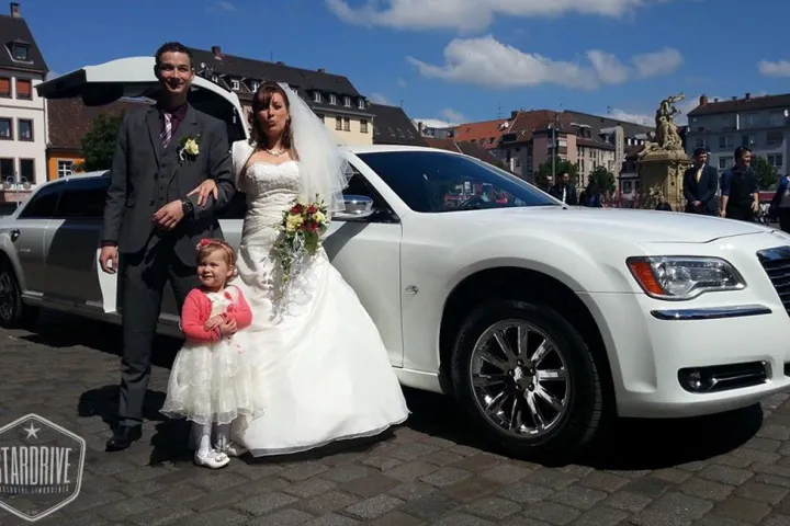 Brautpaar mit Blumenmädchen vor dem weißen Chrysler 300C