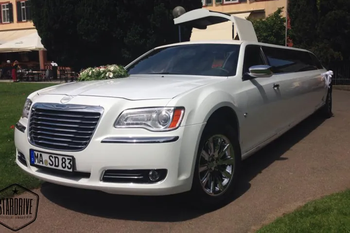 Weißer Chrysler 300C mit Flügeltür und Hochzeitsschmuck