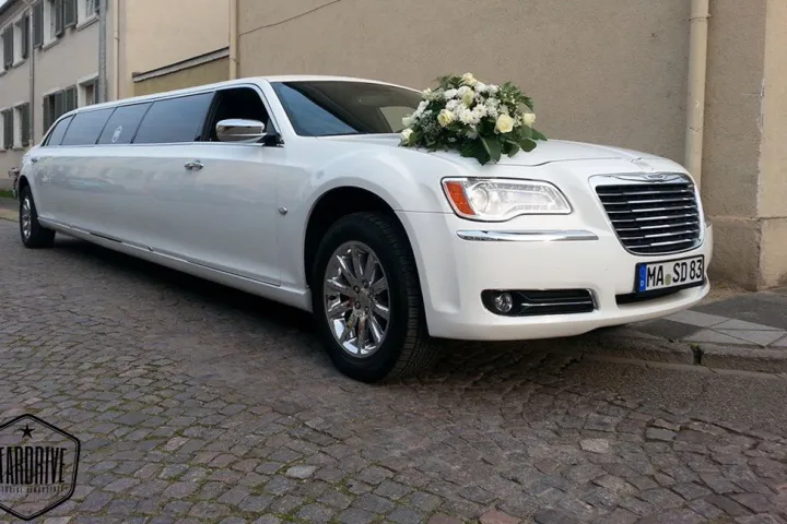 Weißer Chrysler 300C mit Blumenschmuck vor einem Gebäude