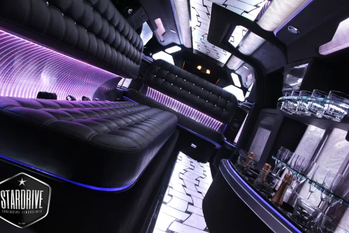 Innenraum einer Stretch-Limousine mit schwarzen Ledersitzen und violettem Licht