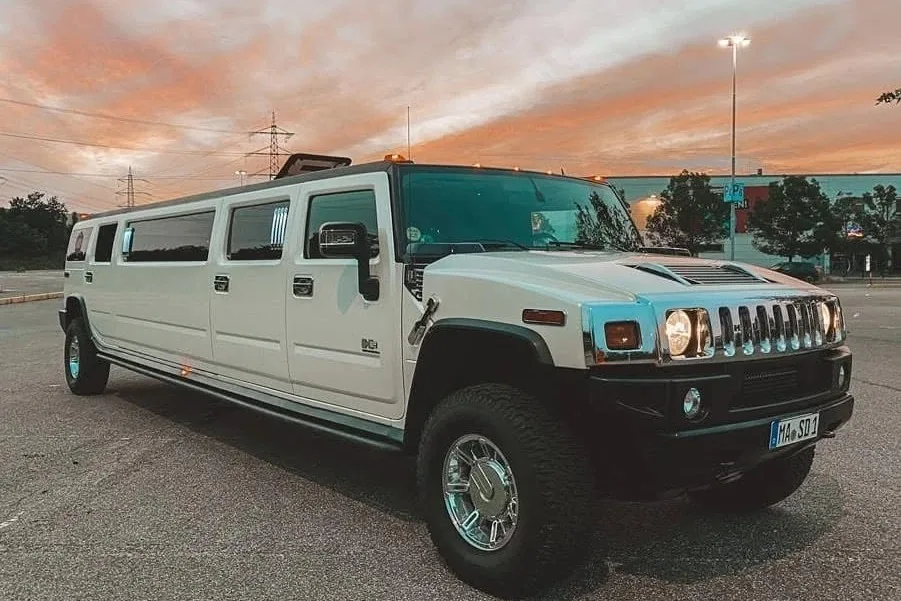 Weißer Hummer H2 als Stretch-Limousine im Abendrot auf einem Parkplatz