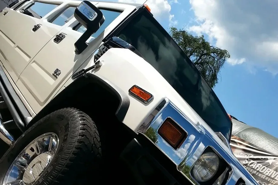 Weißer Hummer H2 im Detail: Kühlergrill, Chromfelge und Seitenspiegel vor blauem Himmel