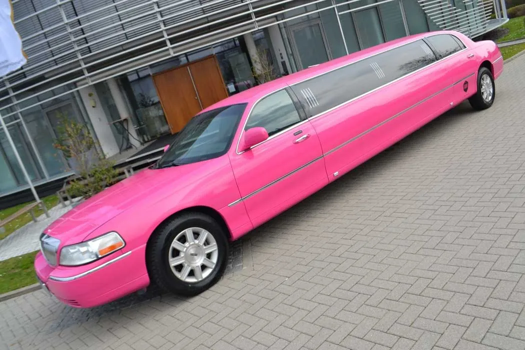 Pinke Stretch-Limousine Lincoln Pink in der Seitenansicht vor einem modernen Gebäude
