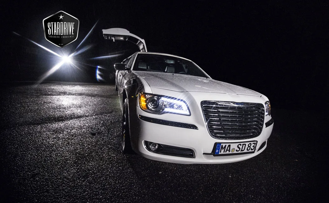 Weißer Chrysler 300C mit Flügeltür bei Nacht im Scheinwerferlicht
