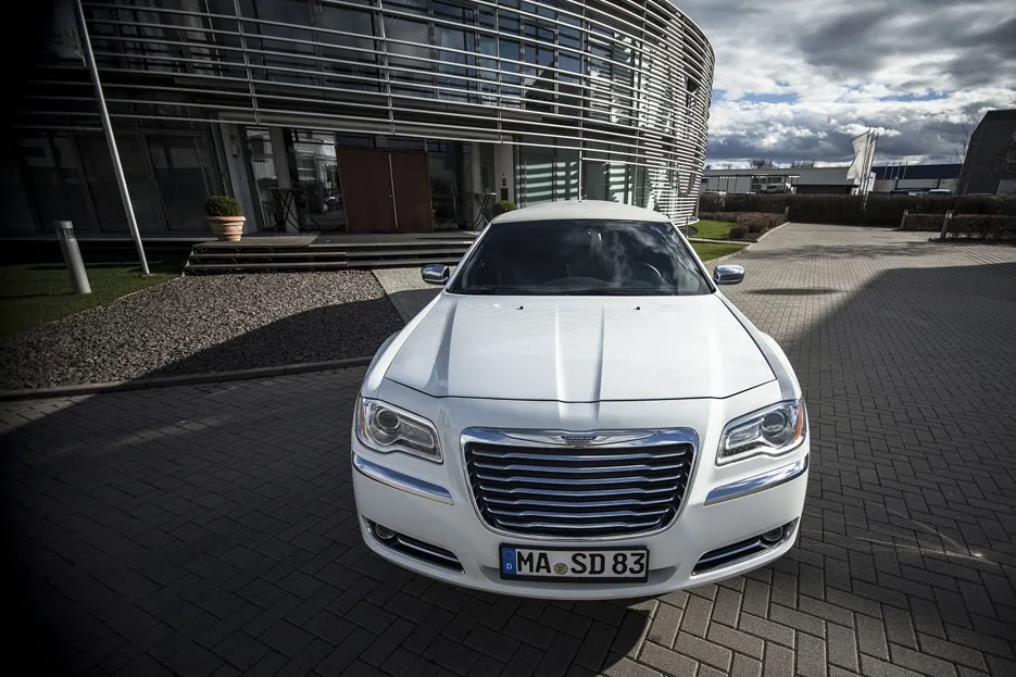 Frontansicht des weißen Chrysler 300C vor einem Bürogebäude