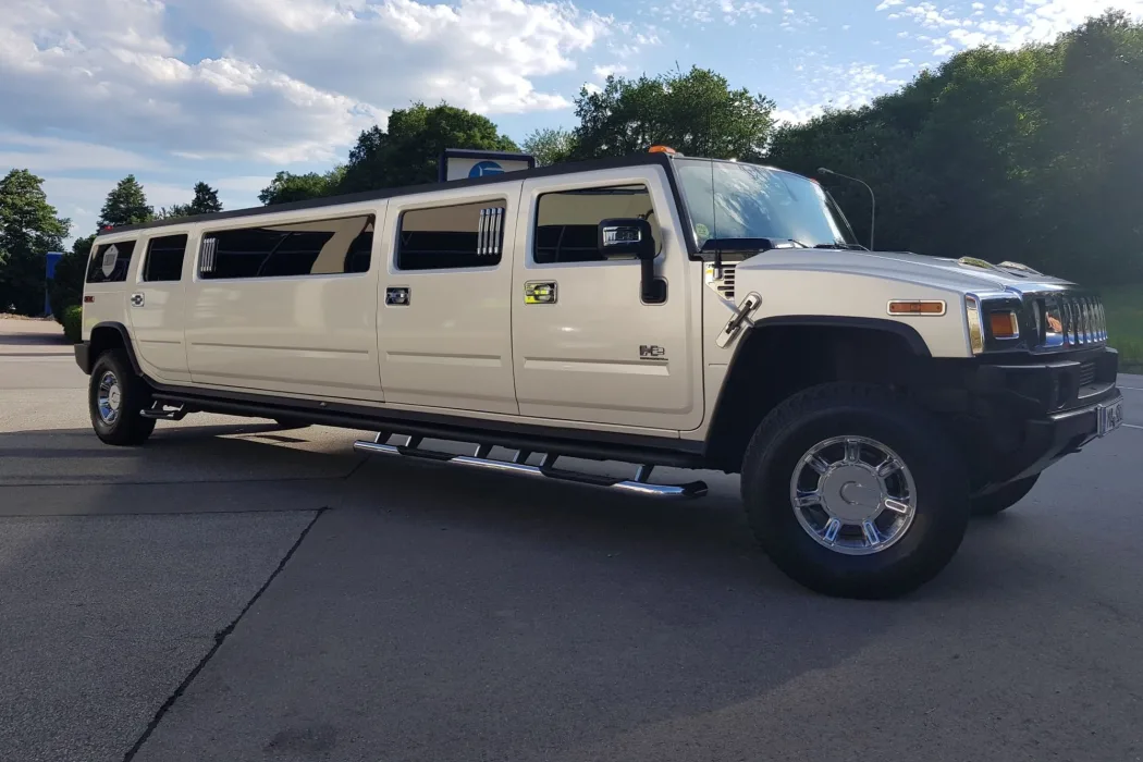 Weiße Hummer-H2-Stretchlimousine im Abendlicht vor Bäumen und bewaldeten Hügeln